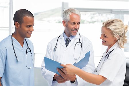 examination folder - Three smiling doctors examining a file in a bright office Stock Photo - Budget Royalty-Free & Subscription, Code: 400-06879475
