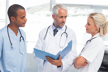 examination folder - Three doctors examining a file in a bright office Stock Photo - Budget Royalty-Free & Subscription, Code: 400-06879473