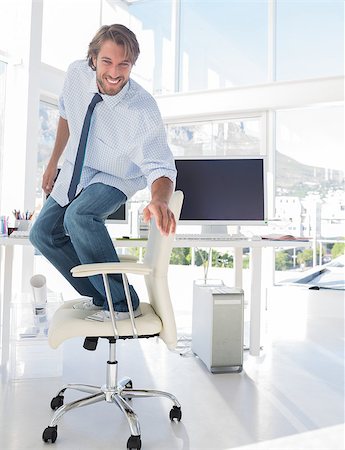 simsearch:400-06885294,k - Man surfing his office chair and smiling in modern office Stockbilder - Microstock & Abonnement, Bildnummer: 400-06879768