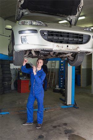 simsearch:400-06870137,k - Full length portrait of male mechanic working under raised car in workshop Photographie de stock - Aubaine LD & Abonnement, Code: 400-06870026