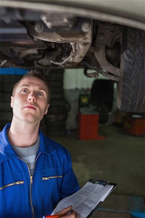 simsearch:400-06870097,k - Young male mechanic with clipboard examining car in garage Foto de stock - Super Valor sin royalties y Suscripción, Código: 400-06870034