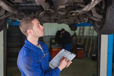simsearch:400-06870097,k - Male mechanic under car preparing checklist in workshop Foto de stock - Super Valor sin royalties y Suscripción, Código: 400-06870030