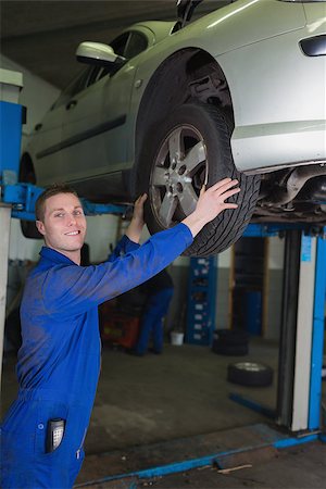 simsearch:400-06870097,k - Car on hydraulic lift as mechanic examining tire in garage Foto de stock - Super Valor sin royalties y Suscripción, Código: 400-06870049