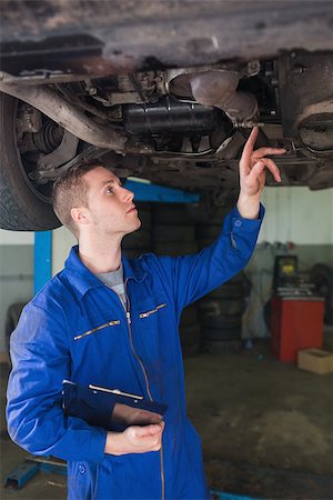 simsearch:400-06870131,k - Male auto mechanic with clipboard examining under car in workshop Photographie de stock - Aubaine LD & Abonnement, Code: 400-06870058