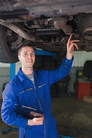 simsearch:400-06870131,k - Portrait of male mechanic with clipboard examining under car in workshop Photographie de stock - Aubaine LD & Abonnement, Code: 400-06870059