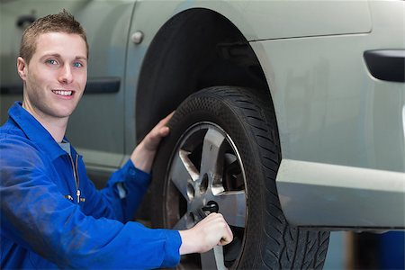 posición de rueda - Portrait of young male mechanic changing car tyre Foto de stock - Super Valor sin royalties y Suscripción, Código: 400-06870079