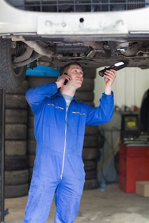 simsearch:400-06870137,k - Young male mechanic on call as he examines under car Photographie de stock - Aubaine LD & Abonnement, Code: 400-06870084