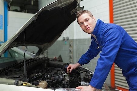 simsearch:400-06870097,k - Portrait of confident male mechanic checking car engine oil Foto de stock - Super Valor sin royalties y Suscripción, Código: 400-06870115
