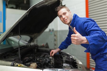simsearch:400-06870137,k - Portrait of mechanic gesturing thumbs up as he checks oil level of car Photographie de stock - Aubaine LD & Abonnement, Code: 400-06870116