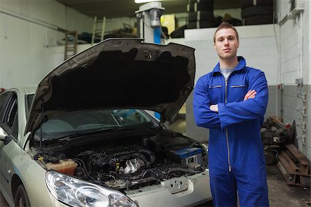 simsearch:400-06870137,k - Portrait of confident auto mechanic standing by car with open hood Photographie de stock - Aubaine LD & Abonnement, Code: 400-06870126