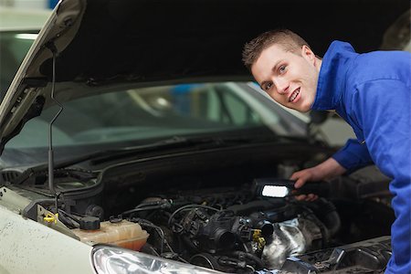 simsearch:400-06870137,k - Portrait of confident repairman with flashlight examining car engine Photographie de stock - Aubaine LD & Abonnement, Code: 400-06870138