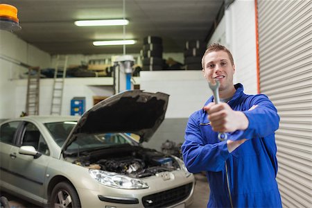 simsearch:400-06870137,k - Portrait of young male mechanic offering spanner in worshop Photographie de stock - Aubaine LD & Abonnement, Code: 400-06870130