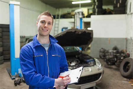 simsearch:400-06870131,k - Portrait of male mechanic writing on clipboard in workshop Photographie de stock - Aubaine LD & Abonnement, Code: 400-06870162