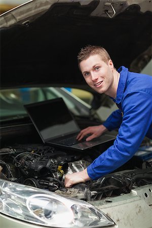 Portrait of happy car mechanic with laptop checking engine Stock Photo - Budget Royalty-Free & Subscription, Code: 400-06870175