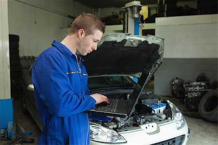 simsearch:400-06870131,k - Male mechanic using laptop with car in background Photographie de stock - Aubaine LD & Abonnement, Code: 400-06870217