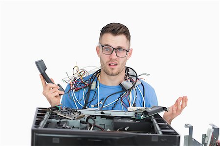 Confused young it professional with cables and phone in front of open cpu over white background Foto de stock - Super Valor sin royalties y Suscripción, Código: 400-06870265