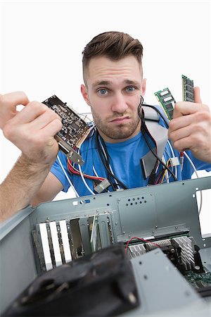 picture of man confused with cable - Portrait of confused young it professional with chips in front of open cpu over white background Stock Photo - Budget Royalty-Free & Subscription, Code: 400-06870268