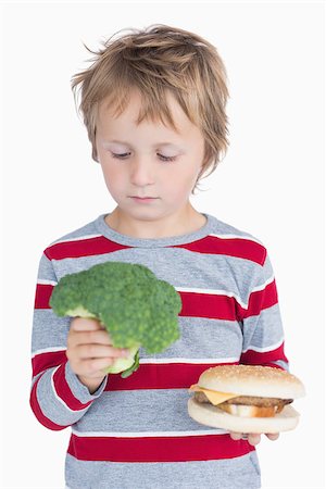Young boy holding broccoli and burger over white background Stock Photo - Budget Royalty-Free & Subscription, Code: 400-06870515