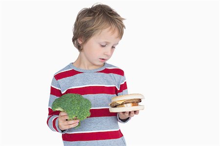 Young boy holding broccoli and burger over white background Stock Photo - Budget Royalty-Free & Subscription, Code: 400-06870513