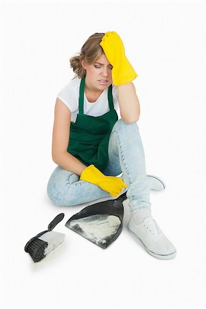simsearch:400-06870646,k - Tired young maid sitting with brush and dust pan over white background Stock Photo - Budget Royalty-Free & Subscription, Code: 400-06870645