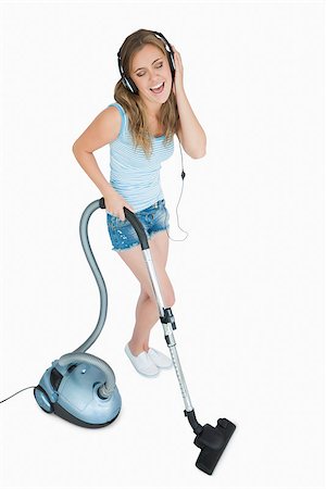 Young woman enjoying music over headphones while vacuuming against white background Stock Photo - Budget Royalty-Free & Subscription, Code: 400-06870676