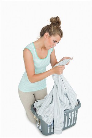 simsearch:400-06870642,k - Young woman looking at shirt collar with laundry basket over white background Stock Photo - Budget Royalty-Free & Subscription, Code: 400-06870680