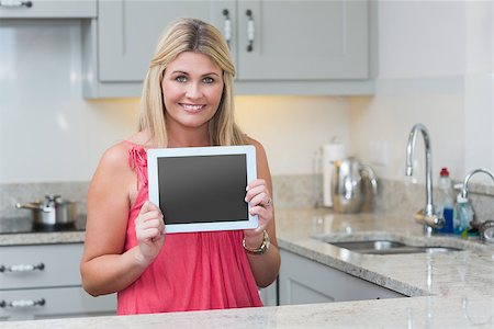 Portrait of casual young woman holding digital tablet in the kitchen at home Stock Photo - Budget Royalty-Free & Subscription, Code: 400-06871127
