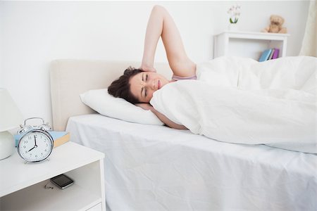 Young woman covering ears in bed with alarm clock on side table Stock Photo - Budget Royalty-Free & Subscription, Code: 400-06871154