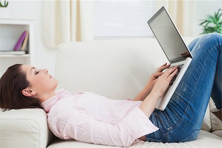 simsearch:400-06872352,k - Side view of casual young woman lying on sofa and using laptop Foto de stock - Royalty-Free Super Valor e Assinatura, Número: 400-06871209