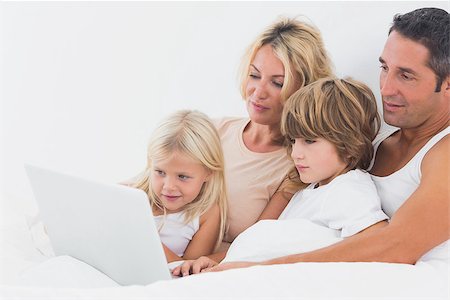 Family watching a laptop screen on a white bed Stock Photo - Budget Royalty-Free & Subscription, Code: 400-06871495