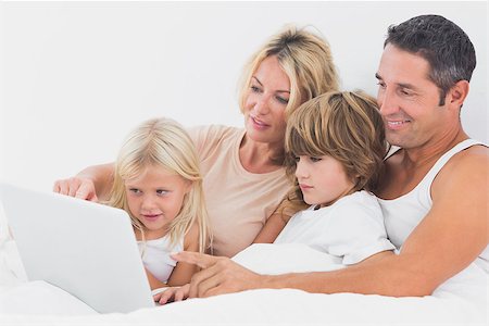 Family watching a laptop screen together on a bed Stock Photo - Budget Royalty-Free & Subscription, Code: 400-06871496