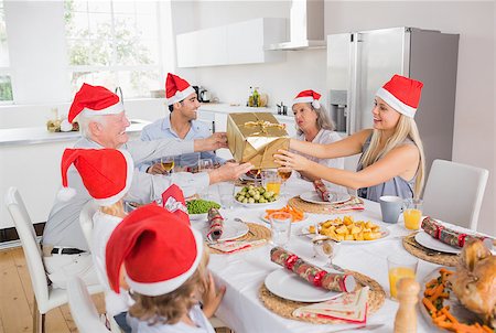 Festive family exchanging gifts at christmas at the dinner table Stock Photo - Budget Royalty-Free & Subscription, Code: 400-06871635