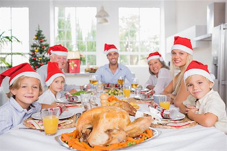 simsearch:400-06871557,k - Happy family wearing santa hats around the dinner table at christmas Photographie de stock - Aubaine LD & Abonnement, Code: 400-06871632