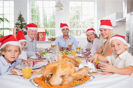simsearch:400-06871557,k - Smiling family around the dinner table at christmas wearing santa hats Photographie de stock - Aubaine LD & Abonnement, Code: 400-06871633