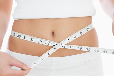 simsearch:400-07936547,k - Closeup midsection of woman measuring waist over white background Foto de stock - Super Valor sin royalties y Suscripción, Código: 400-06871976