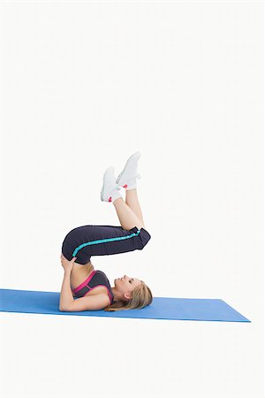 Side view of young woman in the shoulder stand position on yoga mat over white background Stock Photo - Budget Royalty-Free & Subscription, Code: 400-06872094