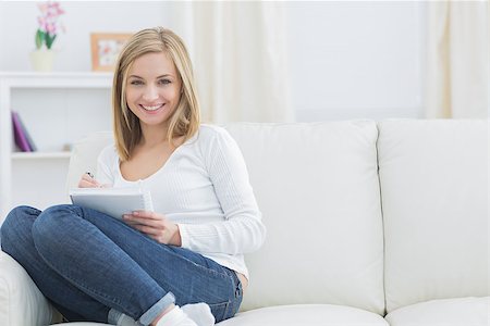 simsearch:400-06872352,k - Portrait of happy young woman with notepad and pen on couch at home Foto de stock - Royalty-Free Super Valor e Assinatura, Número: 400-06872407