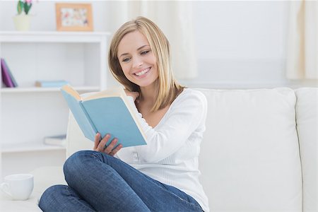 simsearch:400-06872352,k - Happy young woman reading storybook on couch at home Foto de stock - Royalty-Free Super Valor e Assinatura, Número: 400-06872400