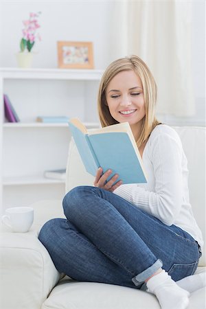 simsearch:400-06872352,k - Happy young woman reading storybook on couch at home Foto de stock - Royalty-Free Super Valor e Assinatura, Número: 400-06872401