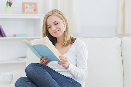 simsearch:400-06872352,k - Happy young woman reading storybook on couch at home Foto de stock - Royalty-Free Super Valor e Assinatura, Número: 400-06872403