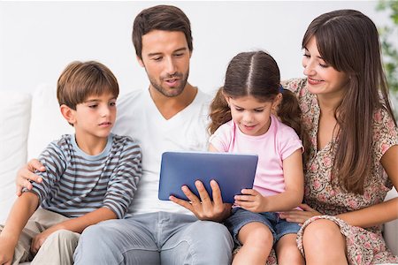 family tablet pc - Happy family looking at tablet pc on the couch Photographie de stock - Aubaine LD & Abonnement, Code: 400-06872909