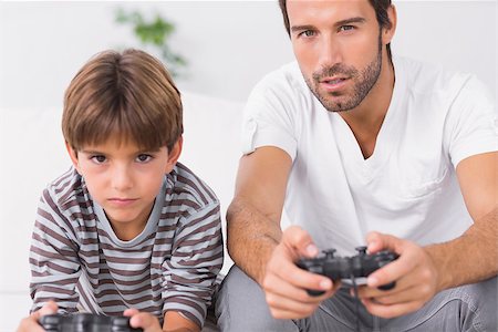 sofa two boys video game - Focused father and son playing video games together on the couch Stock Photo - Budget Royalty-Free & Subscription, Code: 400-06872918