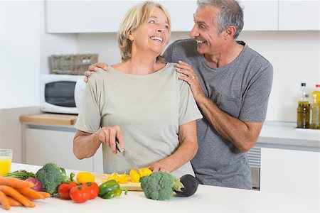 simsearch:400-06874653,k - Smiling couple cutting vegetables together in the kitchen Photographie de stock - Aubaine LD & Abonnement, Code: 400-06873240