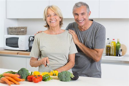 simsearch:400-06874653,k - Happy couple cutting vegetables together in the kitchen Photographie de stock - Aubaine LD & Abonnement, Code: 400-06873241