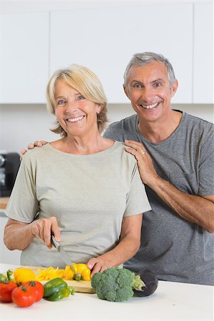 simsearch:400-06874653,k - Cheerful couple cutting vegetables together in the kitchen Photographie de stock - Aubaine LD & Abonnement, Code: 400-06873242