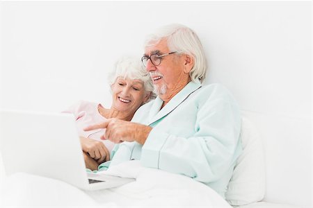 Happy elderly couple using laptop in bed Stock Photo - Budget Royalty-Free & Subscription, Code: 400-06873389