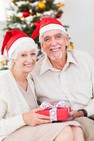 Smiling old couple swapping christmas gifts on the couch Stock Photo - Budget Royalty-Free & Subscription, Code: 400-06873455