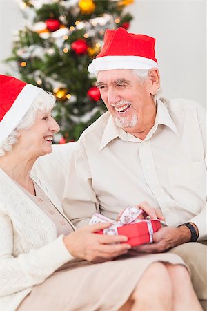 Elderly couple exchanging christmas gifts on couch Stock Photo - Budget Royalty-Free & Subscription, Code: 400-06873453