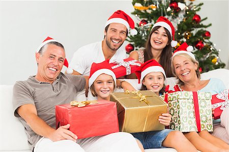 simsearch:400-06874653,k - Happy family at christmas holding gifts on the couch Photographie de stock - Aubaine LD & Abonnement, Code: 400-06873477