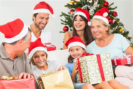 simsearch:400-06874610,k - Happy family at christmas swapping gifts on the couch Foto de stock - Super Valor sin royalties y Suscripción, Código: 400-06873478